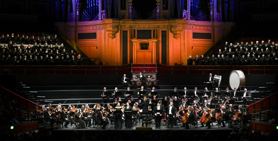 The Royal Philharmonic Orchestra performing on stage with the Philharmonia Chorus behind and above them in the choir stalls.