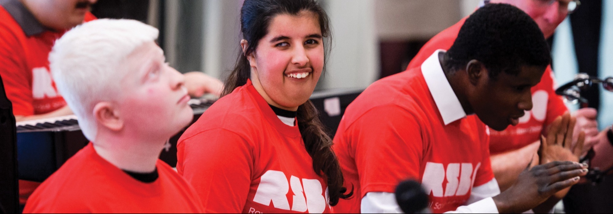 Young people with Royal Society for Blind Children shirts smiling and playing instruments