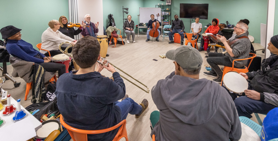 Participants in a Brent Sound Sanctuary session playing instruments in a circle with RPO musicians